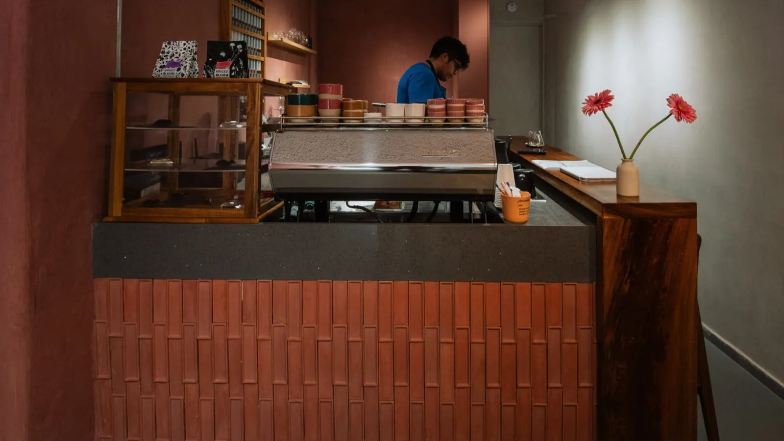 Barista working the espresso machine, colorful cups stacked on the bar